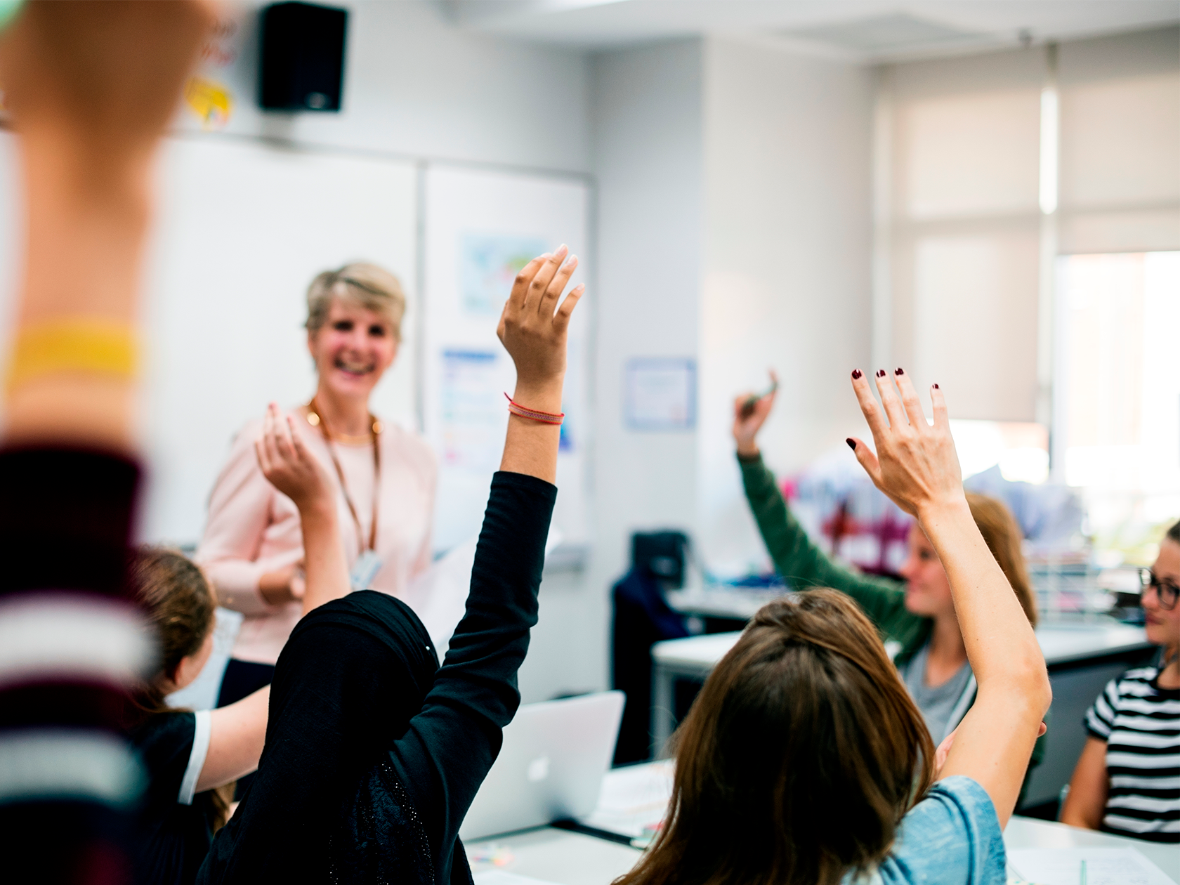 Elever som räcker upp handen i ett klassrum