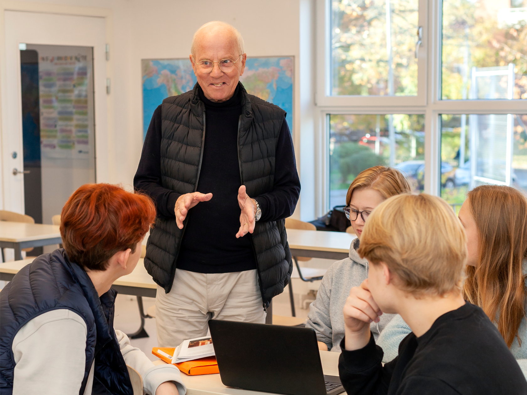 Lärare pratar med elever som sitter vid ett bord