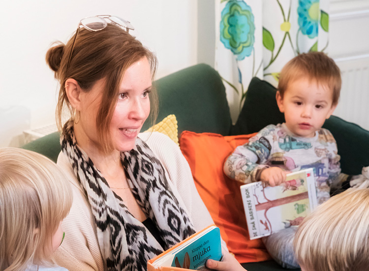 Förskole lärare som pratar med förskole barn i en soffa