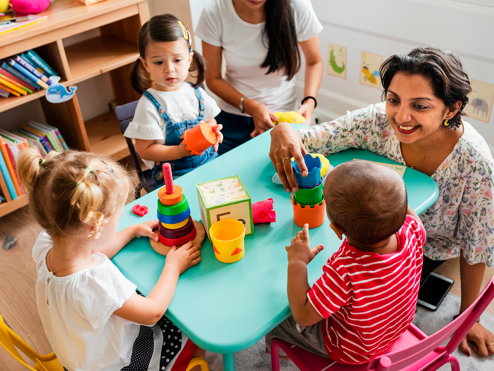 Förskolebarn som leker vid ett bord med lärare